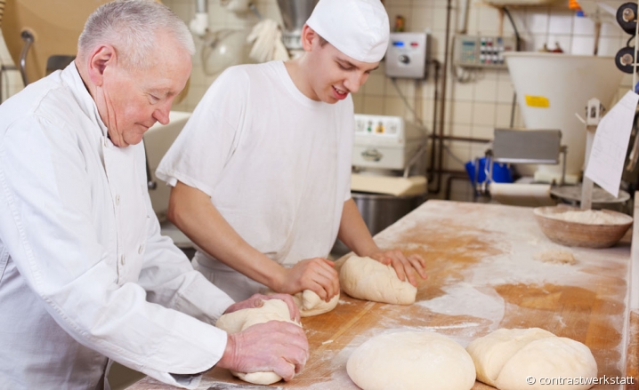 Artisan boulanger pétrissant des pâtons aux côtés de son apprenti